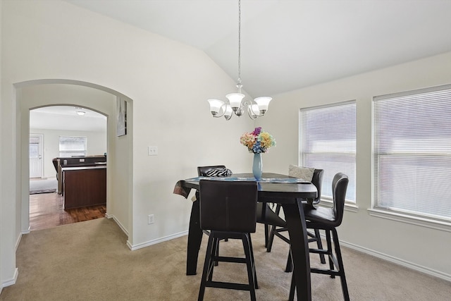 carpeted dining space featuring lofted ceiling and an inviting chandelier