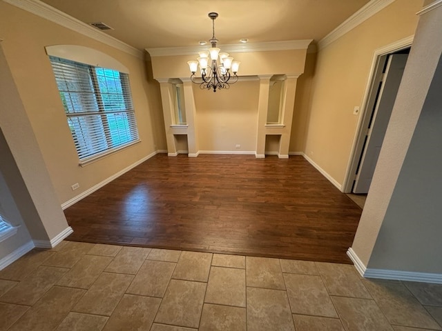 unfurnished dining area featuring ornamental molding, an inviting chandelier, decorative columns, and hardwood / wood-style flooring