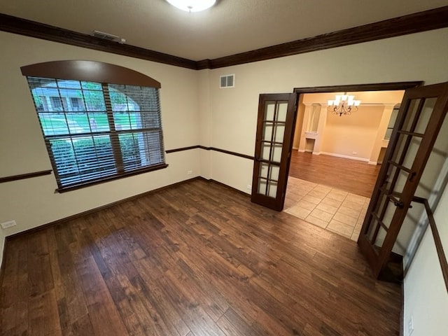 empty room with wood-type flooring, french doors, crown molding, and a chandelier