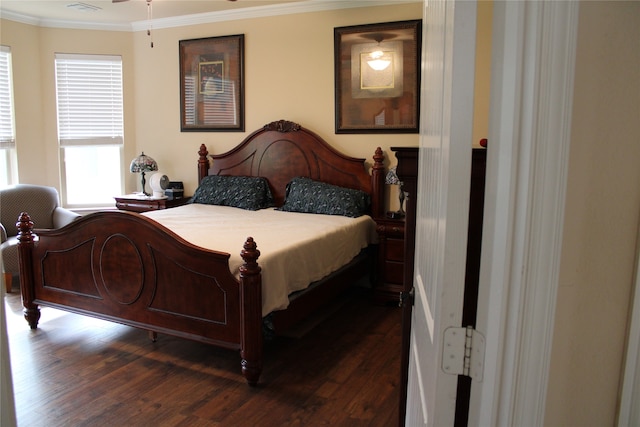 bedroom featuring dark wood-type flooring, crown molding, and multiple windows