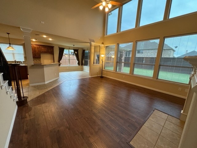 unfurnished living room with ornate columns, tile patterned floors, and ceiling fan