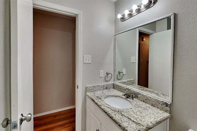 bathroom featuring wood-type flooring and vanity with extensive cabinet space