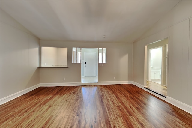 spare room featuring vaulted ceiling and hardwood / wood-style flooring