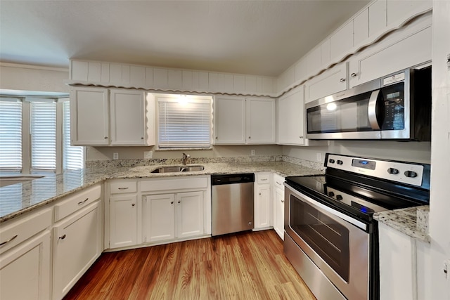 kitchen with white cabinets, appliances with stainless steel finishes, sink, and light hardwood / wood-style flooring