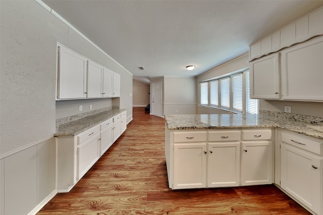 kitchen featuring light hardwood / wood-style floors, light stone counters, white cabinets, and kitchen peninsula