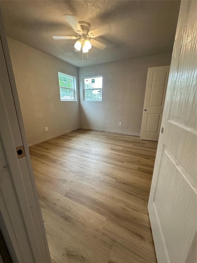 unfurnished room featuring ceiling fan, light hardwood / wood-style floors, and a textured ceiling