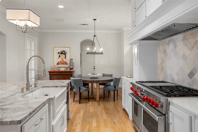 kitchen with hanging light fixtures, custom range hood, light hardwood / wood-style flooring, white cabinets, and double oven range