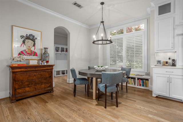 dining area featuring light hardwood / wood-style floors, ornamental molding, and a notable chandelier