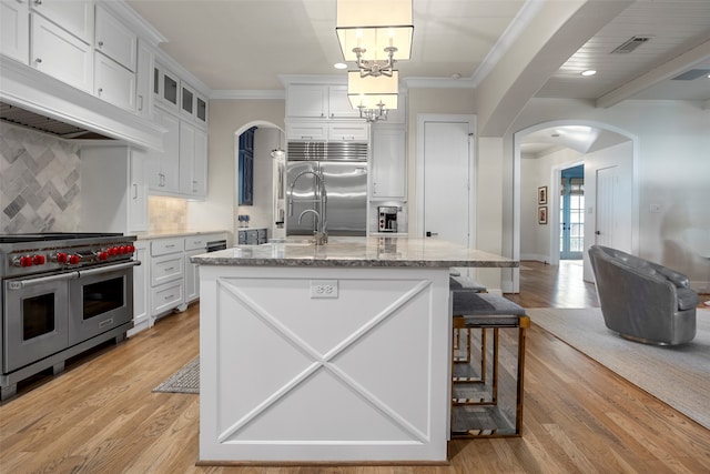 kitchen featuring premium appliances, white cabinetry, tasteful backsplash, and pendant lighting