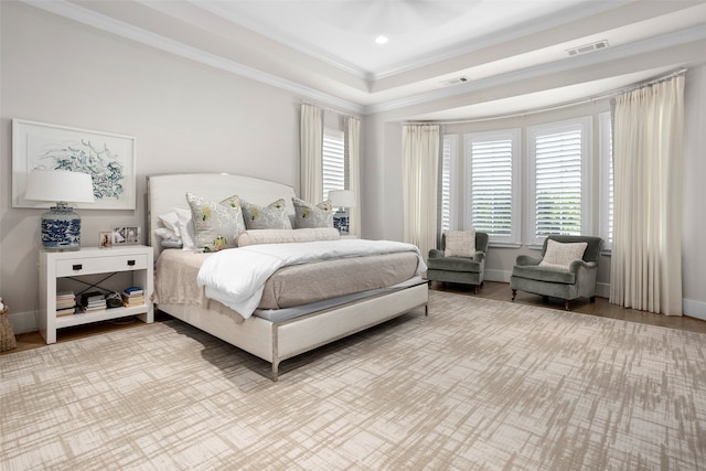 bedroom featuring ornamental molding, a tray ceiling, and hardwood / wood-style flooring