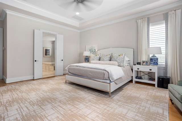 bedroom with a raised ceiling, ceiling fan, and ensuite bath