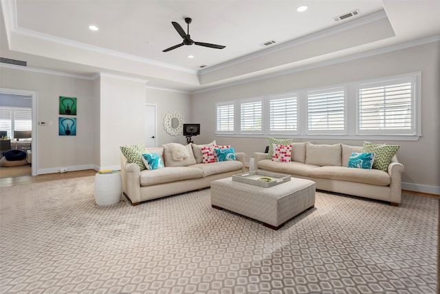 living room with ceiling fan, ornamental molding, and a tray ceiling