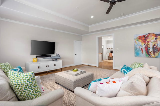 living room with crown molding, ceiling fan, hardwood / wood-style floors, and a raised ceiling