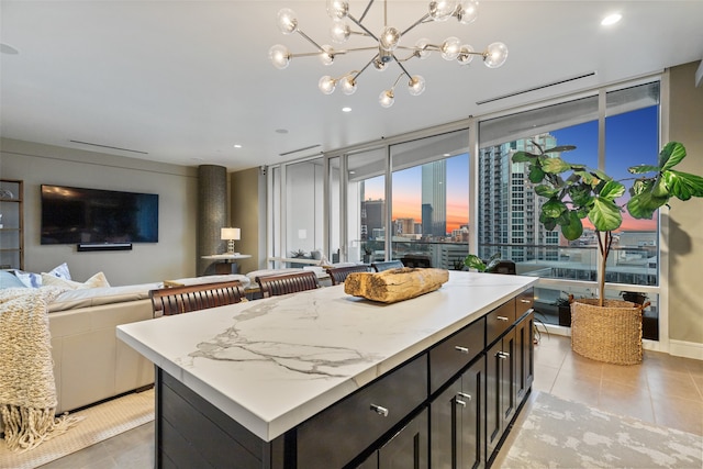 kitchen featuring light tile flooring, a kitchen island, dark brown cabinetry, and an inviting chandelier