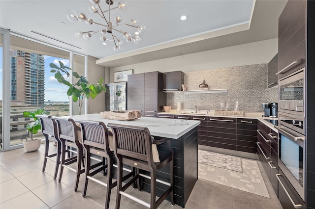 kitchen with wall oven, dark brown cabinets, tasteful backsplash, oven, and a kitchen island