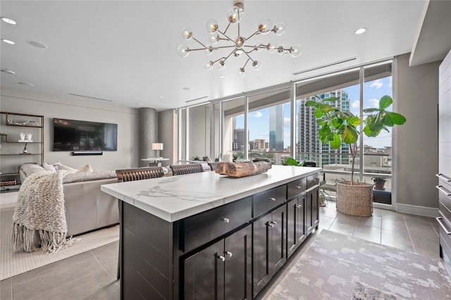 kitchen featuring an inviting chandelier, light stone counters, a kitchen island, and light tile floors