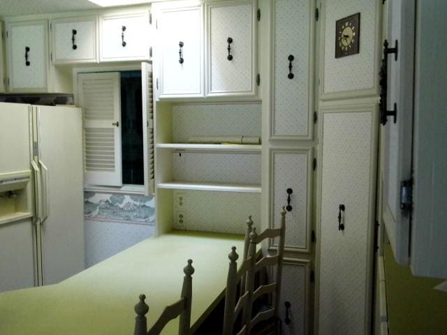 kitchen with white cabinetry and white refrigerator with ice dispenser