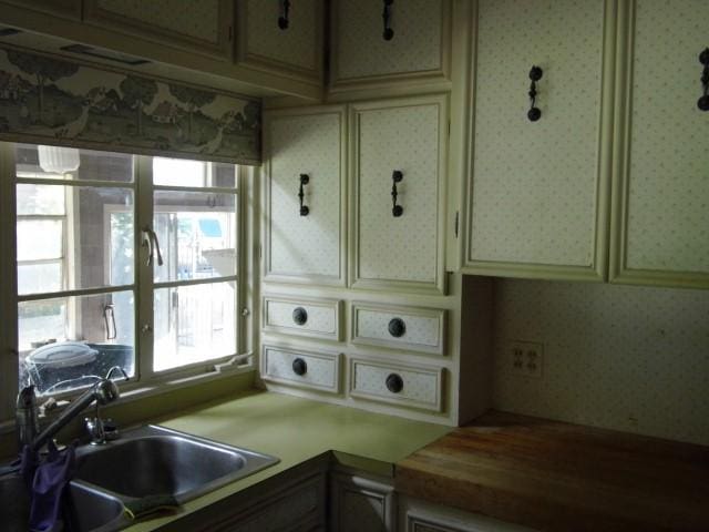 kitchen with a wealth of natural light, cream cabinets, and sink