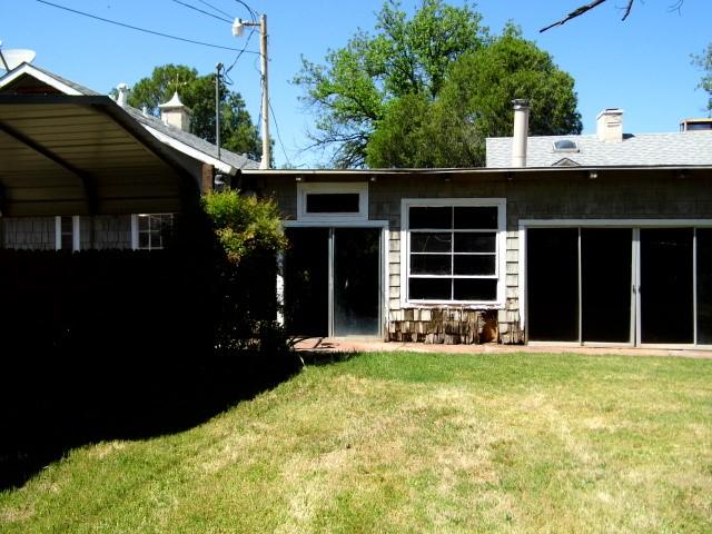 rear view of house with a lawn and a carport