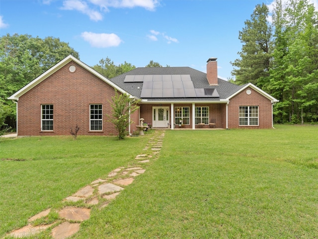 back of house with solar panels, a porch, and a lawn