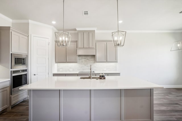 kitchen with hanging light fixtures, sink, an island with sink, and stainless steel appliances