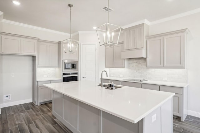 kitchen with sink, an island with sink, gray cabinetry, stainless steel appliances, and dark hardwood / wood-style flooring