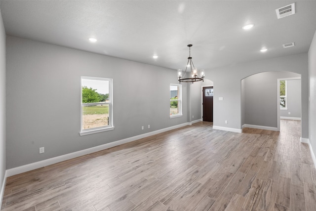 spare room featuring a chandelier, light hardwood / wood-style floors, and a textured ceiling