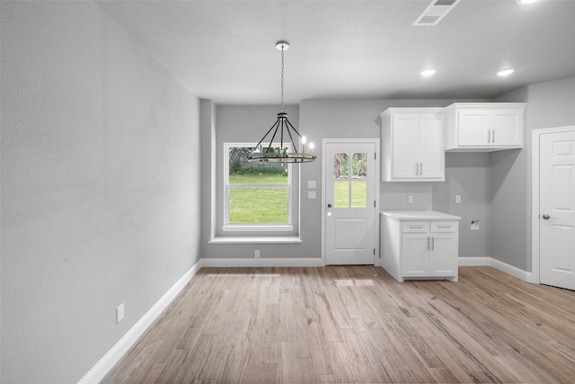 kitchen with white cabinets, decorative light fixtures, light hardwood / wood-style floors, and an inviting chandelier