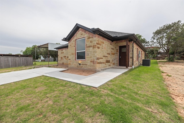 back of property featuring central AC unit, a lawn, driveway, and a shingled roof