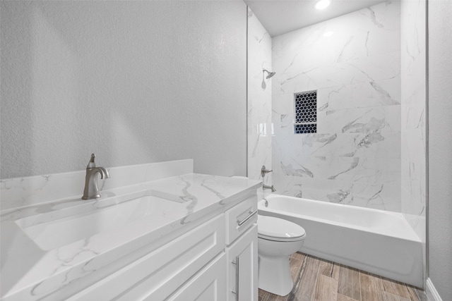 full bathroom featuring vanity, tiled shower / bath combo, and toilet