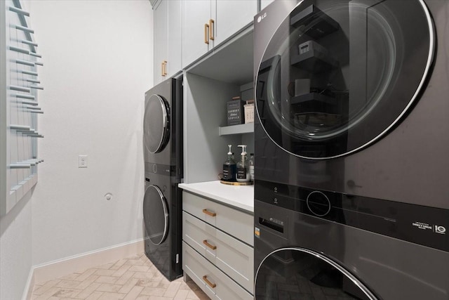 laundry room with stacked washer / drying machine and cabinets