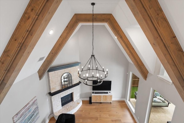 living room with an inviting chandelier, high vaulted ceiling, light wood-type flooring, beamed ceiling, and a fireplace