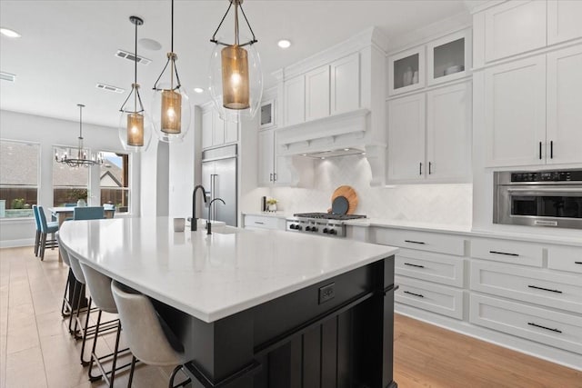 kitchen featuring pendant lighting, stainless steel appliances, and an island with sink