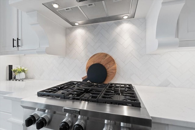 kitchen with stove, decorative backsplash, island range hood, and light stone countertops