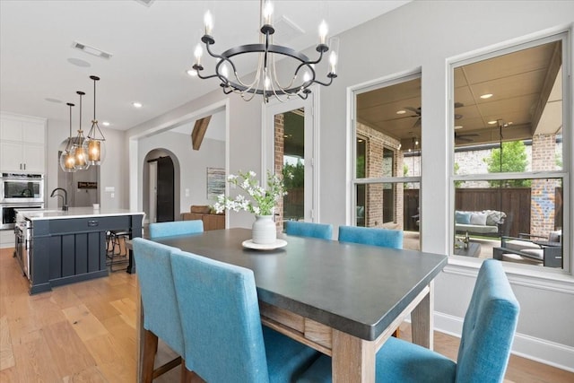 dining space featuring beamed ceiling, ceiling fan with notable chandelier, and light hardwood / wood-style floors