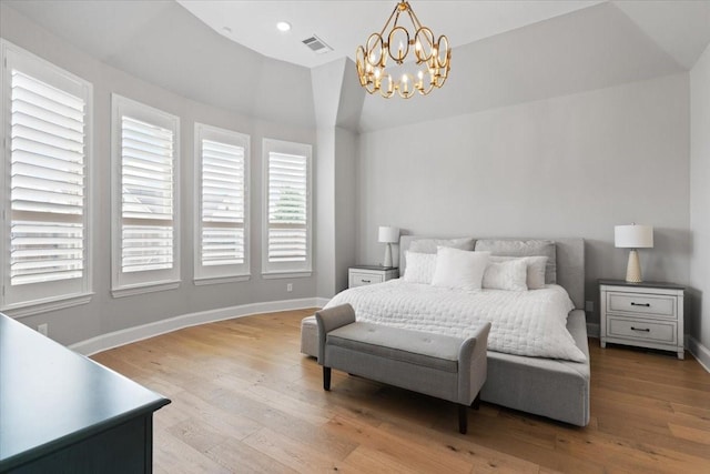 bedroom featuring an inviting chandelier, lofted ceiling, and light hardwood / wood-style floors