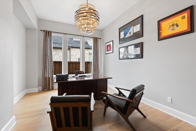 home office with light wood-type flooring and an inviting chandelier