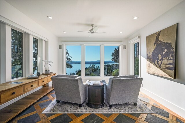 interior space featuring a water view, ceiling fan, and parquet flooring