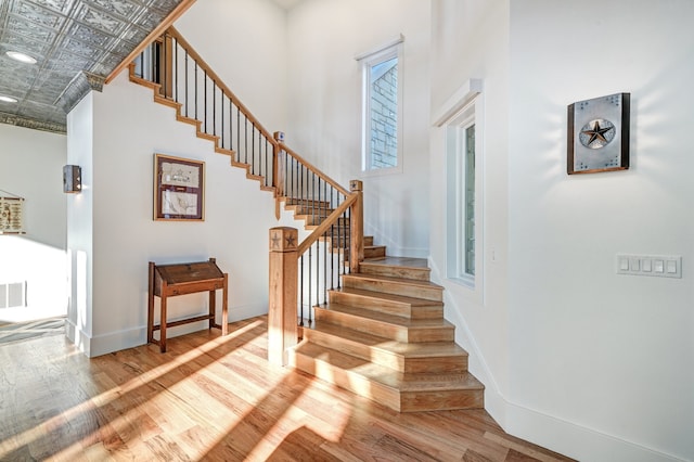 staircase with hardwood / wood-style floors and a towering ceiling