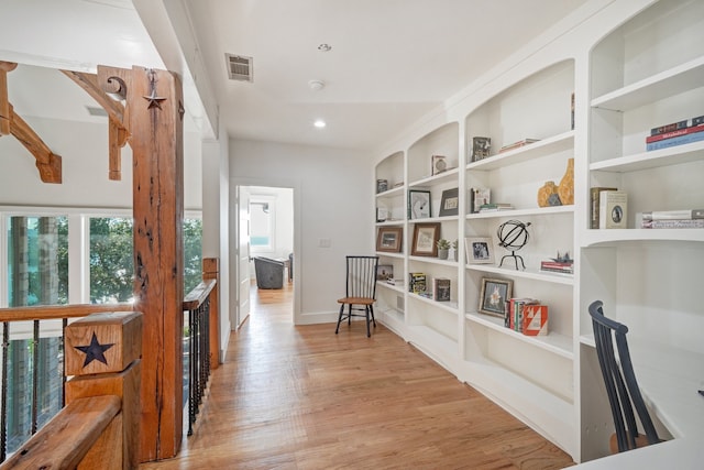 hallway with built in shelves and light hardwood / wood-style floors