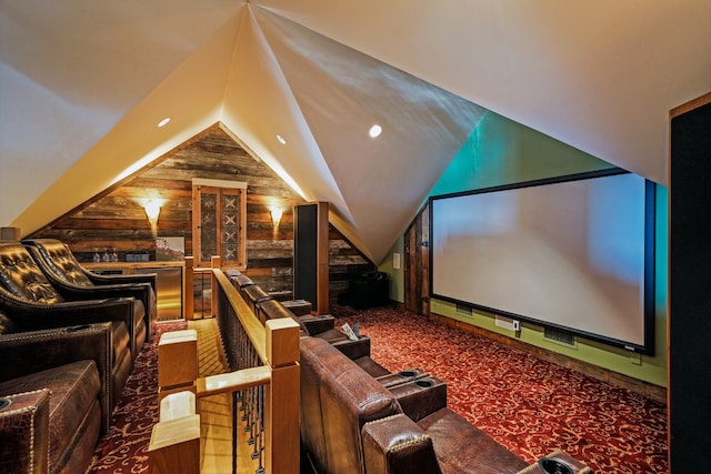 carpeted home theater featuring vaulted ceiling and wooden walls