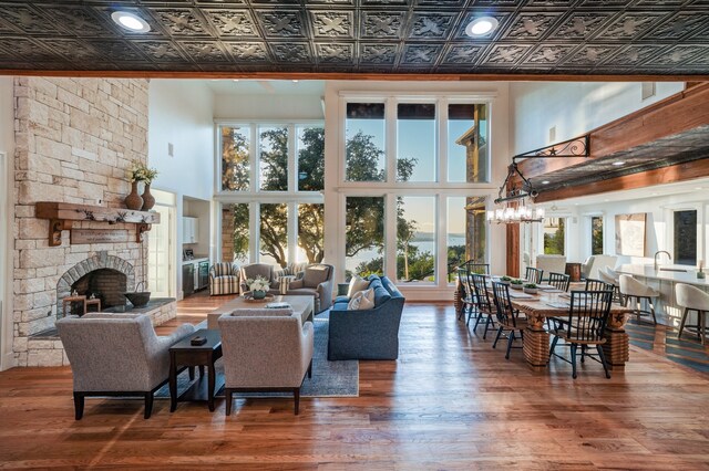 living room featuring a chandelier, a fireplace, hardwood / wood-style flooring, and a high ceiling