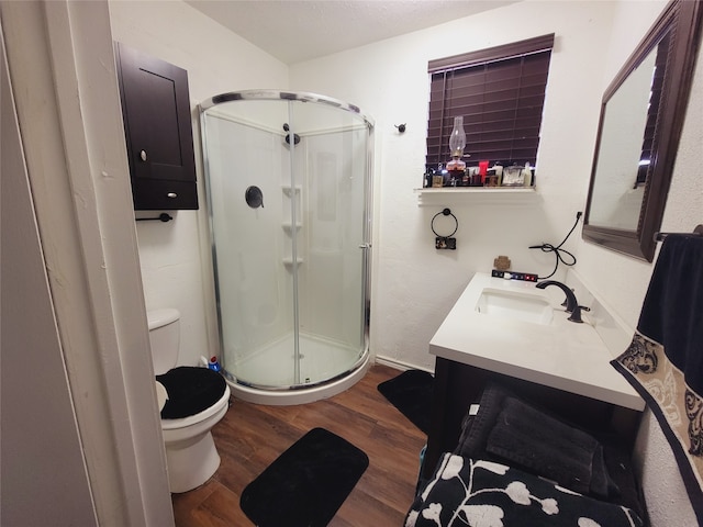 bathroom with a shower with door, hardwood / wood-style flooring, toilet, and vanity