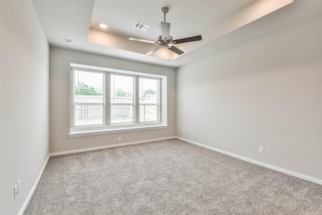spare room featuring baseboards, a ceiling fan, visible vents, a tray ceiling, and carpet