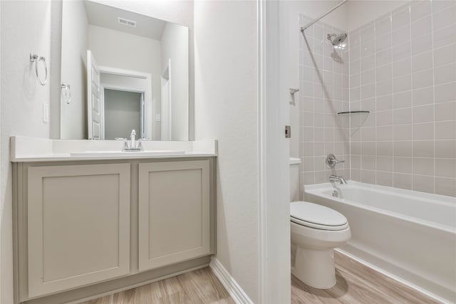 full bathroom featuring tiled shower / bath combo, vanity, hardwood / wood-style floors, and toilet