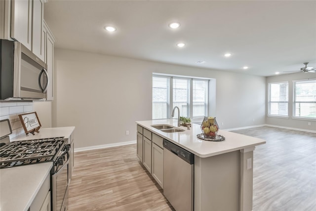 kitchen with a sink, light countertops, light wood finished floors, and stainless steel appliances