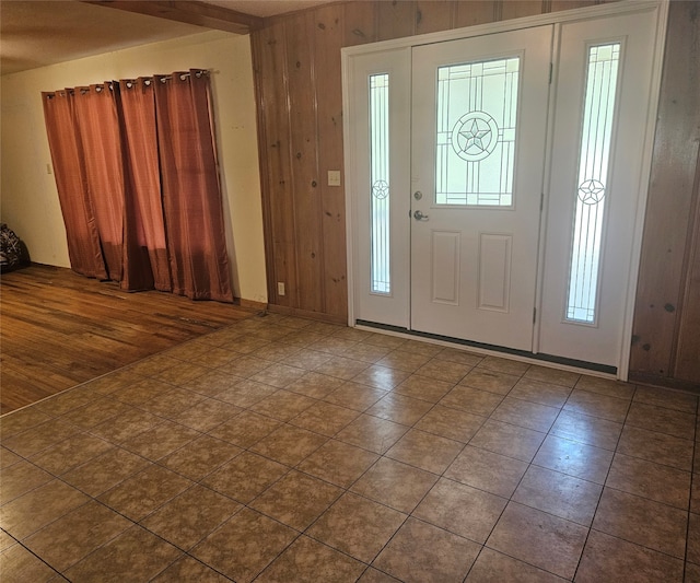 entryway featuring dark tile patterned floors, wood walls, and a wealth of natural light