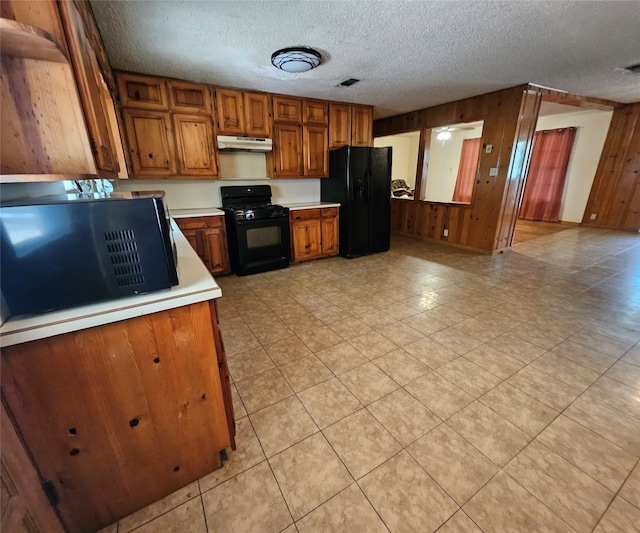 kitchen with a textured ceiling, black appliances, and light tile patterned floors