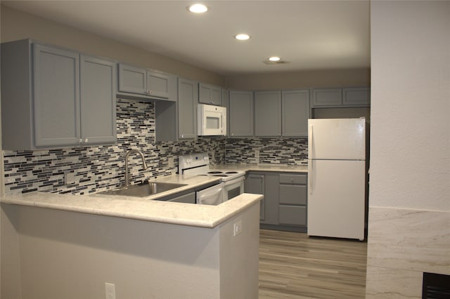 kitchen featuring gray cabinets, kitchen peninsula, white appliances, and light wood-type flooring