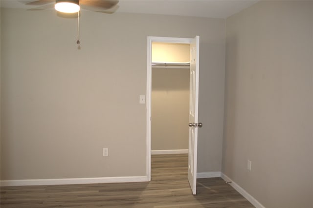 unfurnished bedroom featuring a closet, ceiling fan, a walk in closet, and hardwood / wood-style flooring